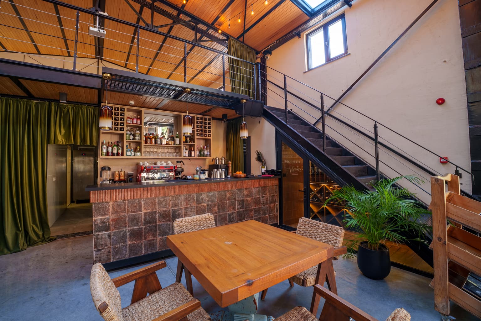 Casa Kilyos'un kapalı salonunda bar, ahşap masa ve asma kata çıkan merdiven