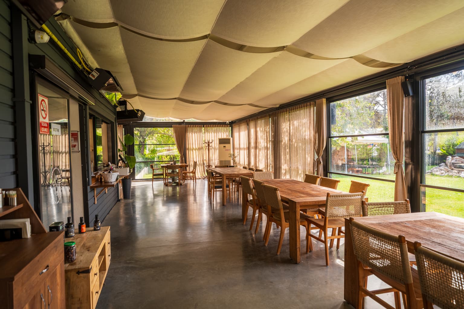 Casa Kilyos restoranının cam cepheli salonu ve uzun ahşap masalar
